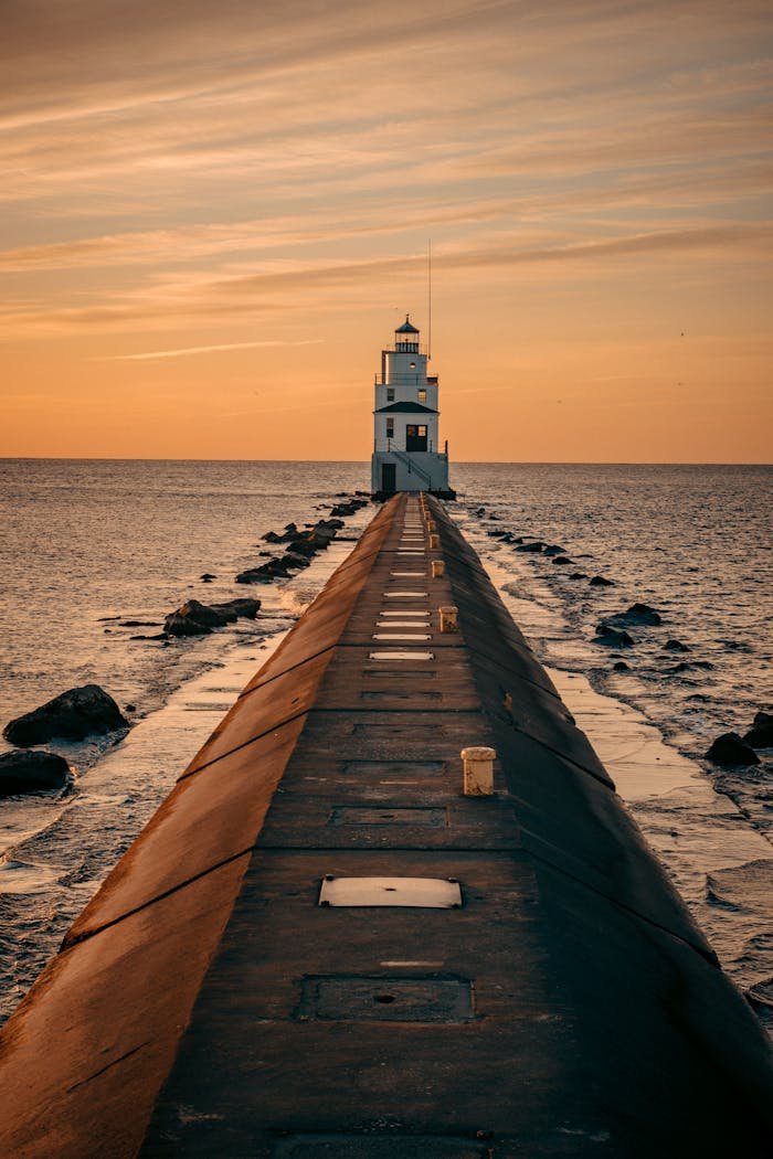 gallery-img-01 Stunning sunset view of the Manitowoc Breakwater Lighthouse, WI, capturing the tranquil ocean and warm skies.