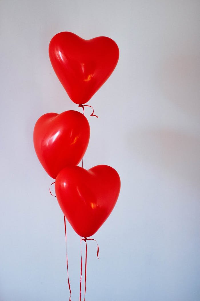 cta-02 Three red heart-shaped balloons floating in a minimalist studio setting, evoking love and romance.