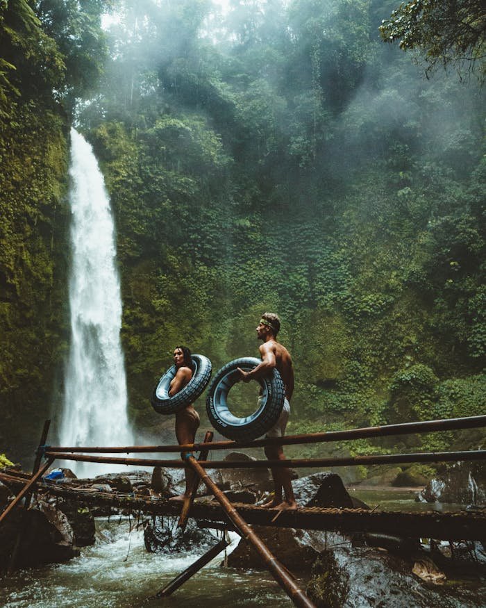why-choose-us-img A couple in swimwear with float tubes exploring a lush waterfall in Bali, Indonesia.